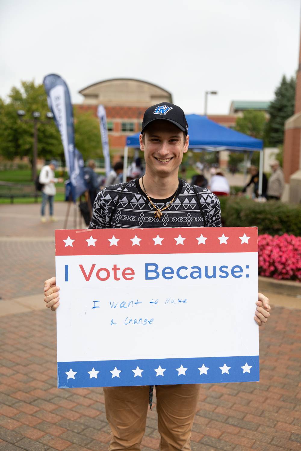 Student holding sign titled "I vote because: I want to make a change"